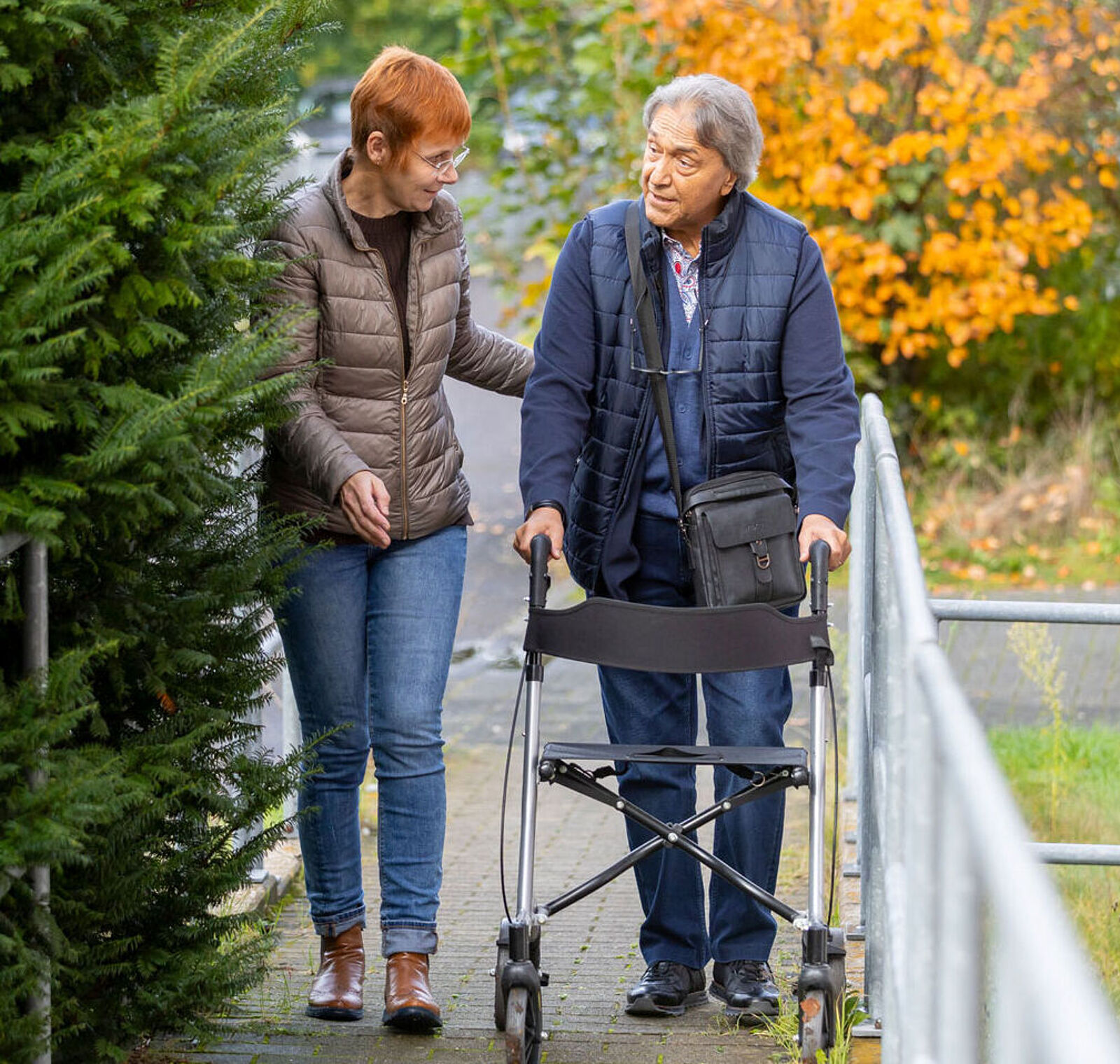 Picture shows a care worker with an elderly gentleman on a rollator.